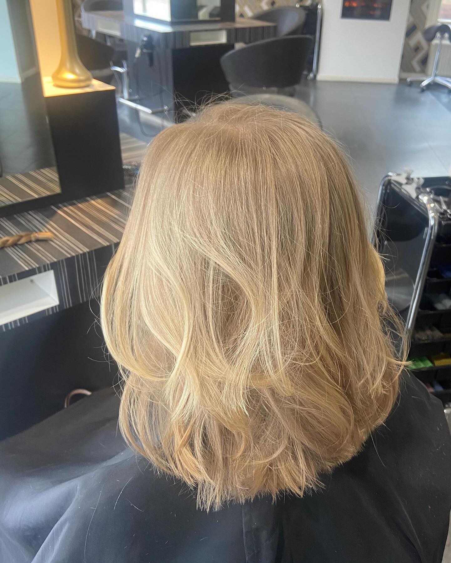 Een blonde bob met zachte slagen, van achteren gezien in de spiegel van de salon