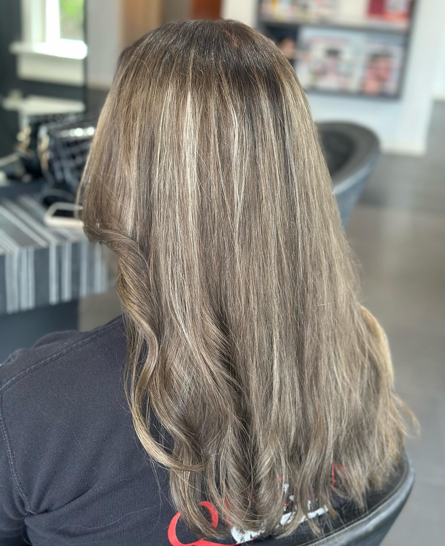 Lang asblond haar met balayage, van achteren gezien in de salon